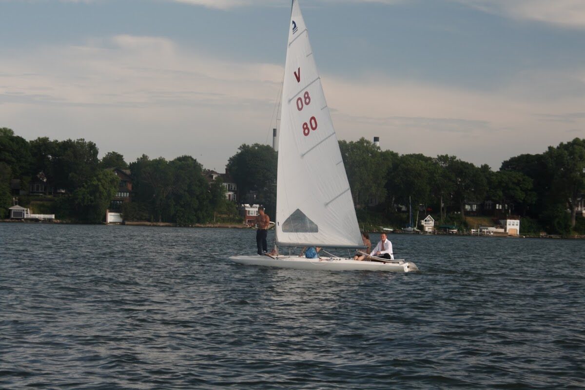 Three sailors heel a dinghy through a gentle puff during a lesson