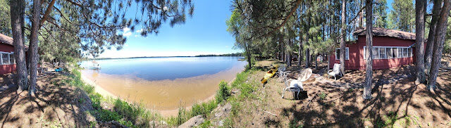 The red office building behind the sand beach, Adirondack chairs facing the water